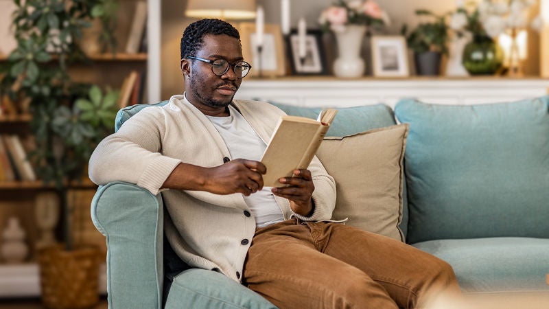 Person sitting on couch reading a book.