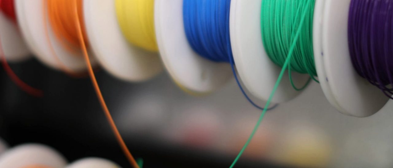 Spools of red, orange, yellow, blue, green, and violet thread.